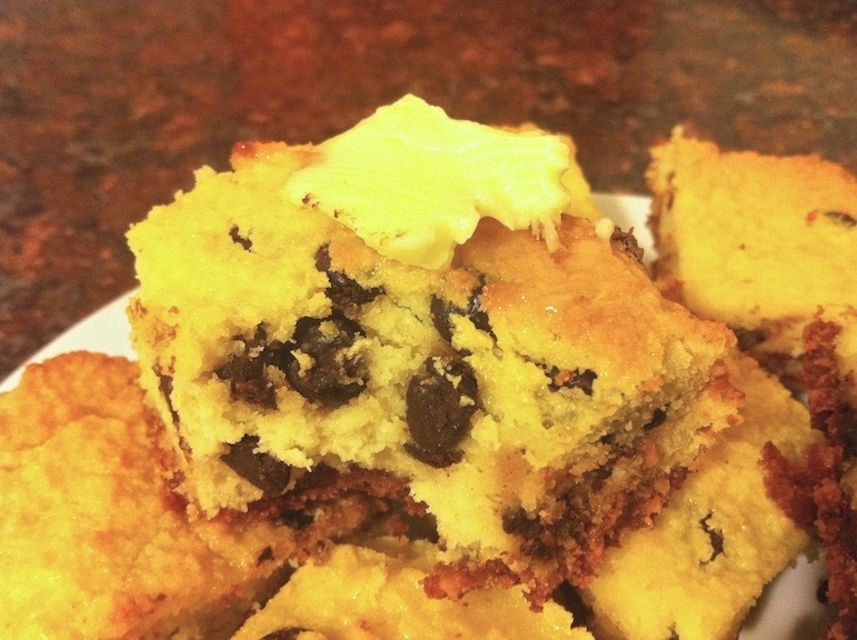 close up of numerous pieces of coconut chocolate chip cake on a white plate