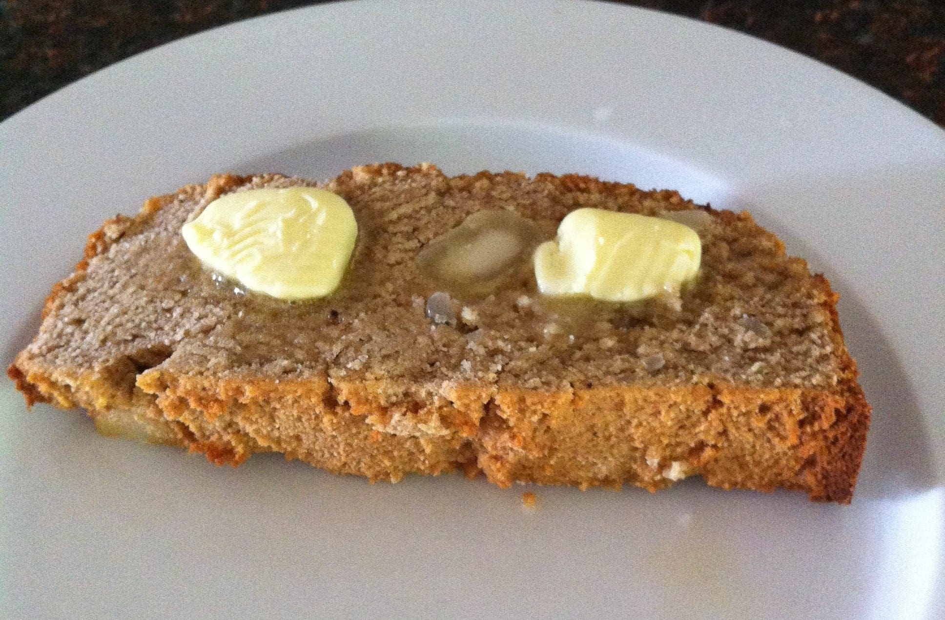 piece of paleo coconut flour macadamia nut banana bread topped with two slabs of butter