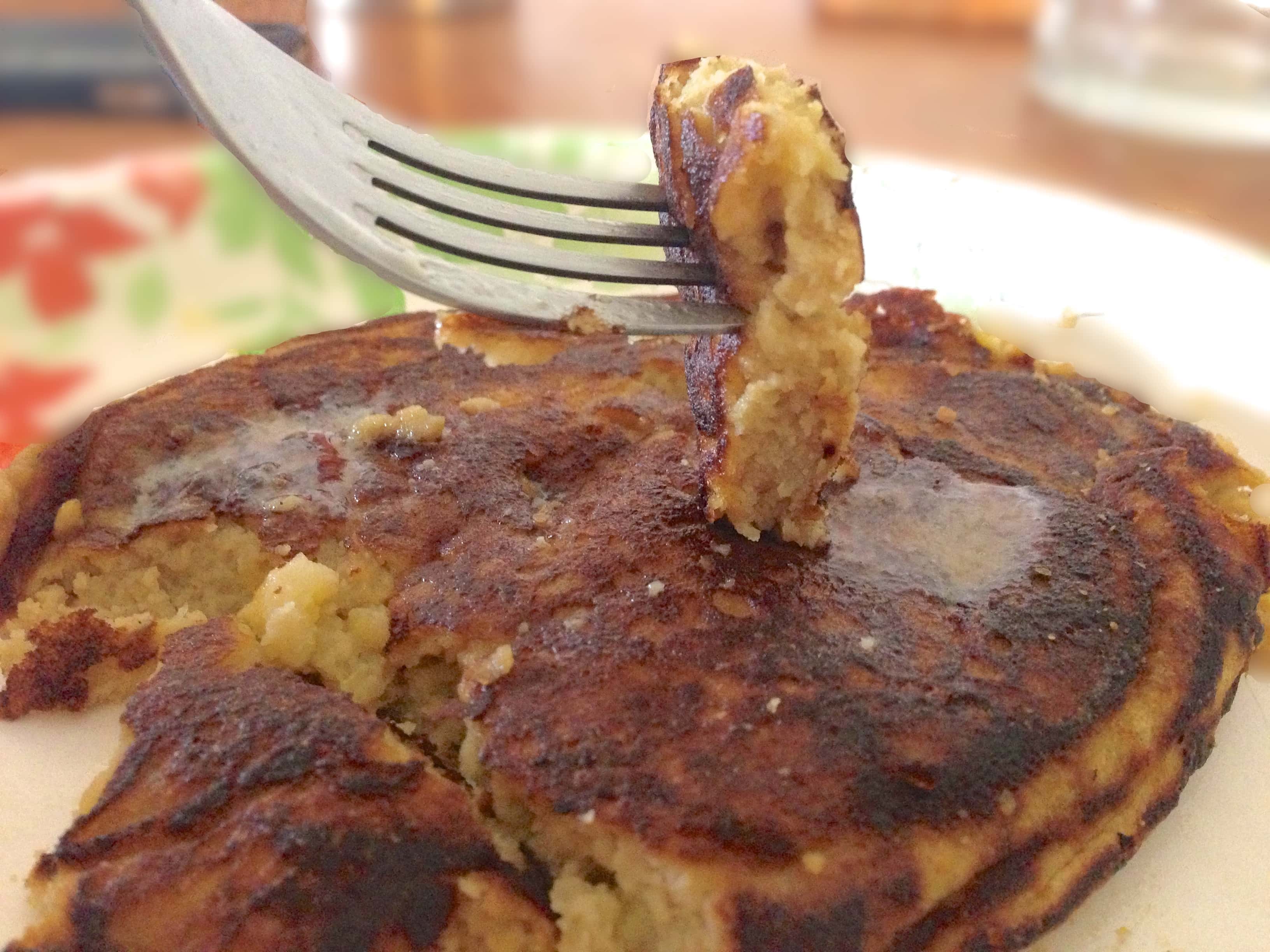 close up of stack of almond flour pancakes with one bite of pancake on a fork just above the stack
