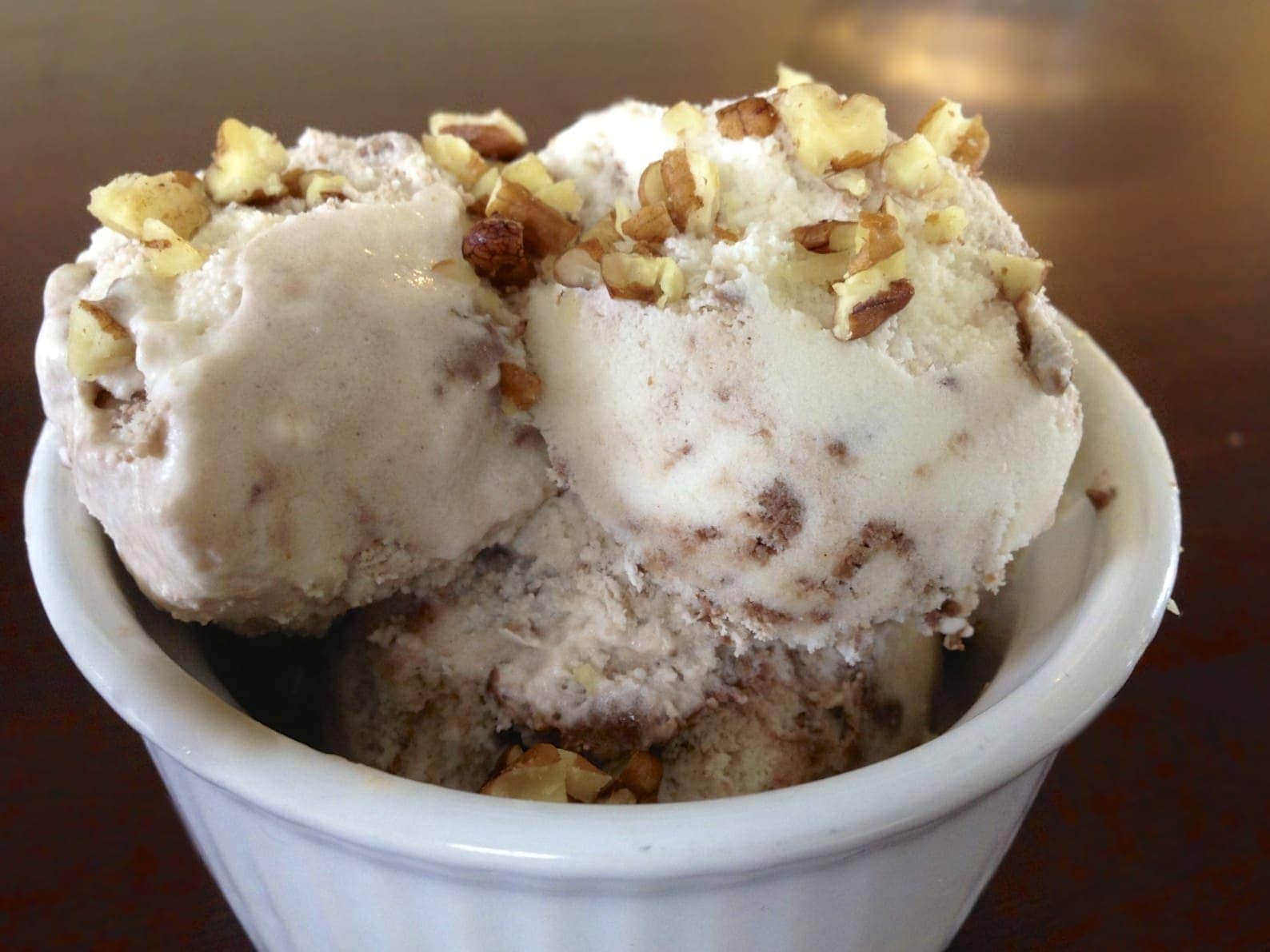 close up of small dish of paleo chocolate fudge swirl ice cream topped with chopped nuts