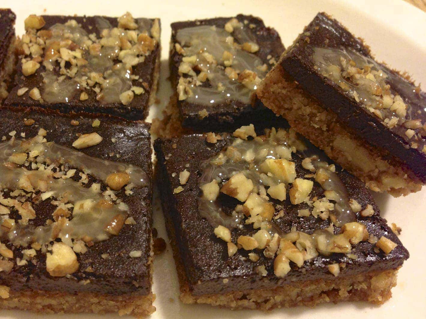 close up of several pieces of paleo chocolate pecan bars  topped with chopped up pecans