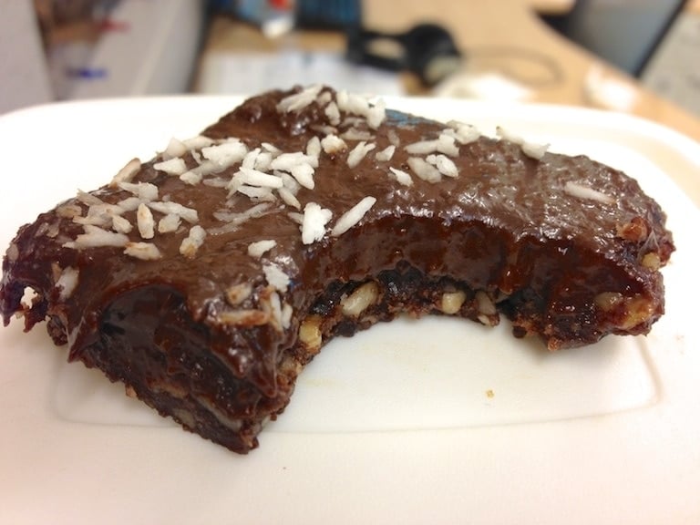 piece of paleo fudge topped with shredded coconut with bite taken out of fudge