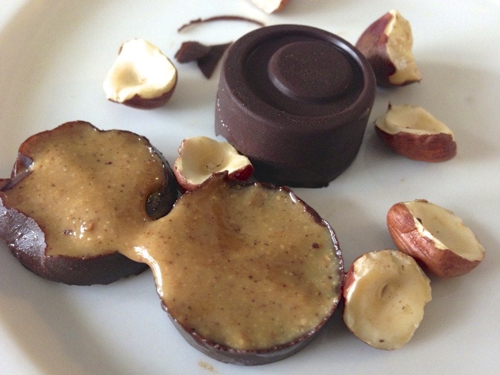 close up of paleo hazelnut cream filled chocolates with one opened up to show inside filling 