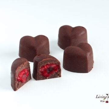 heart shaped paleo raspberry chocolate pieces with one piece in foreground bit into showing inside texture