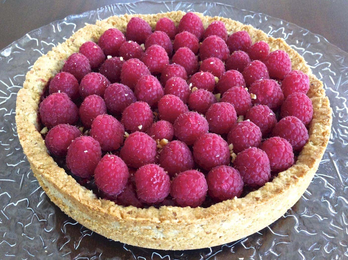 close up of large round paleo mix berry tart loaded with fresh raspberries 