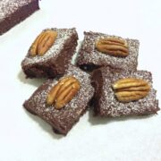 close up of four pieces of chocolate cherry fudge bars topped with one single pecan