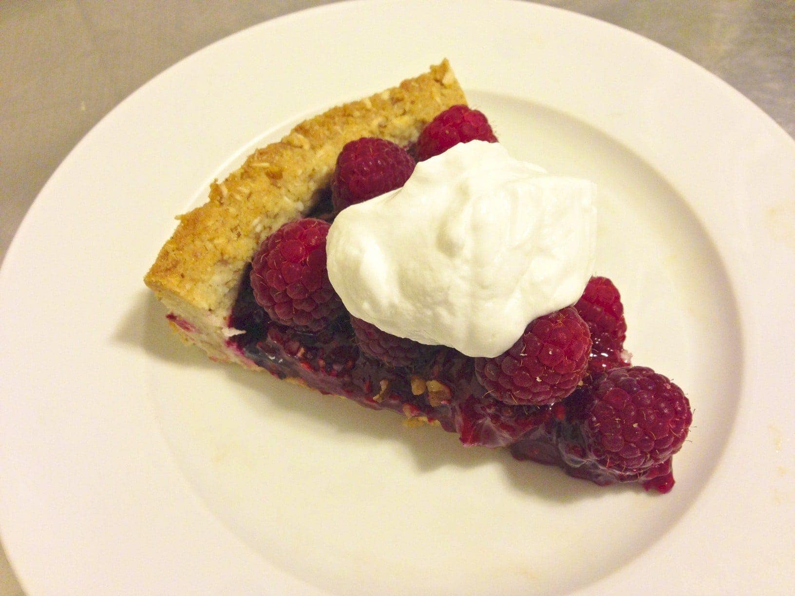 close up of large round paleo mix berry tart loaded with fresh raspberries 
