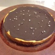 close up of large round paleo chocolate cheesecake topped with pieces of cacao nibs