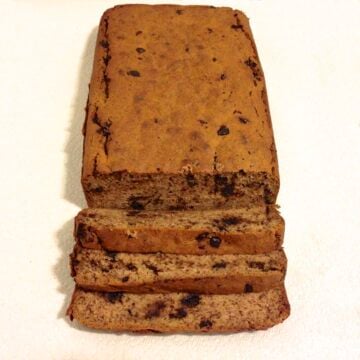 loaf of chocolate chip banana bread with three slices cut and laying down in front of the loaf