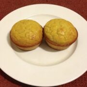 two coconut flour orange muffins on a round white plate
