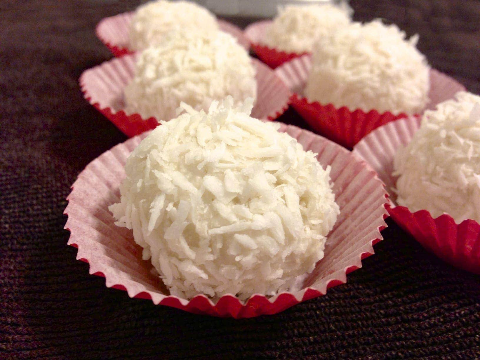 close up of several paleo coconut truffles in red paper cups and they are also known in Brazil as Brigadeiro
