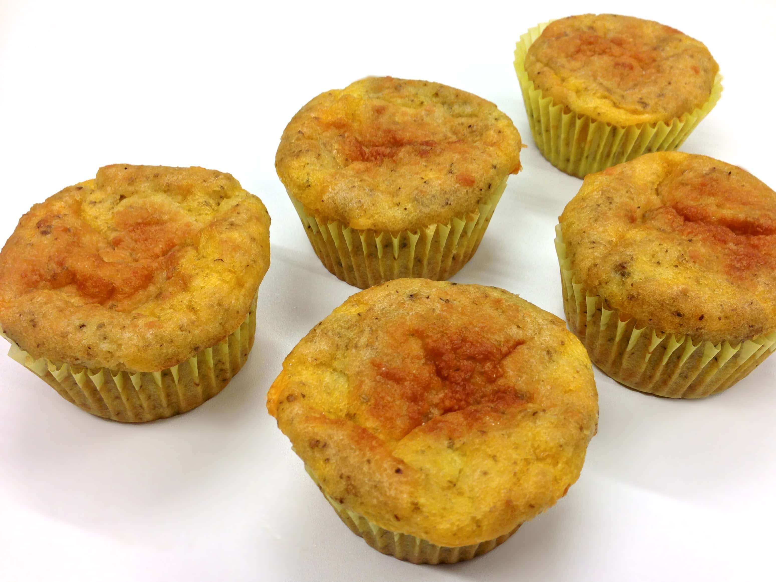 close up of five grain free cheesy oregano muffins on white surface 