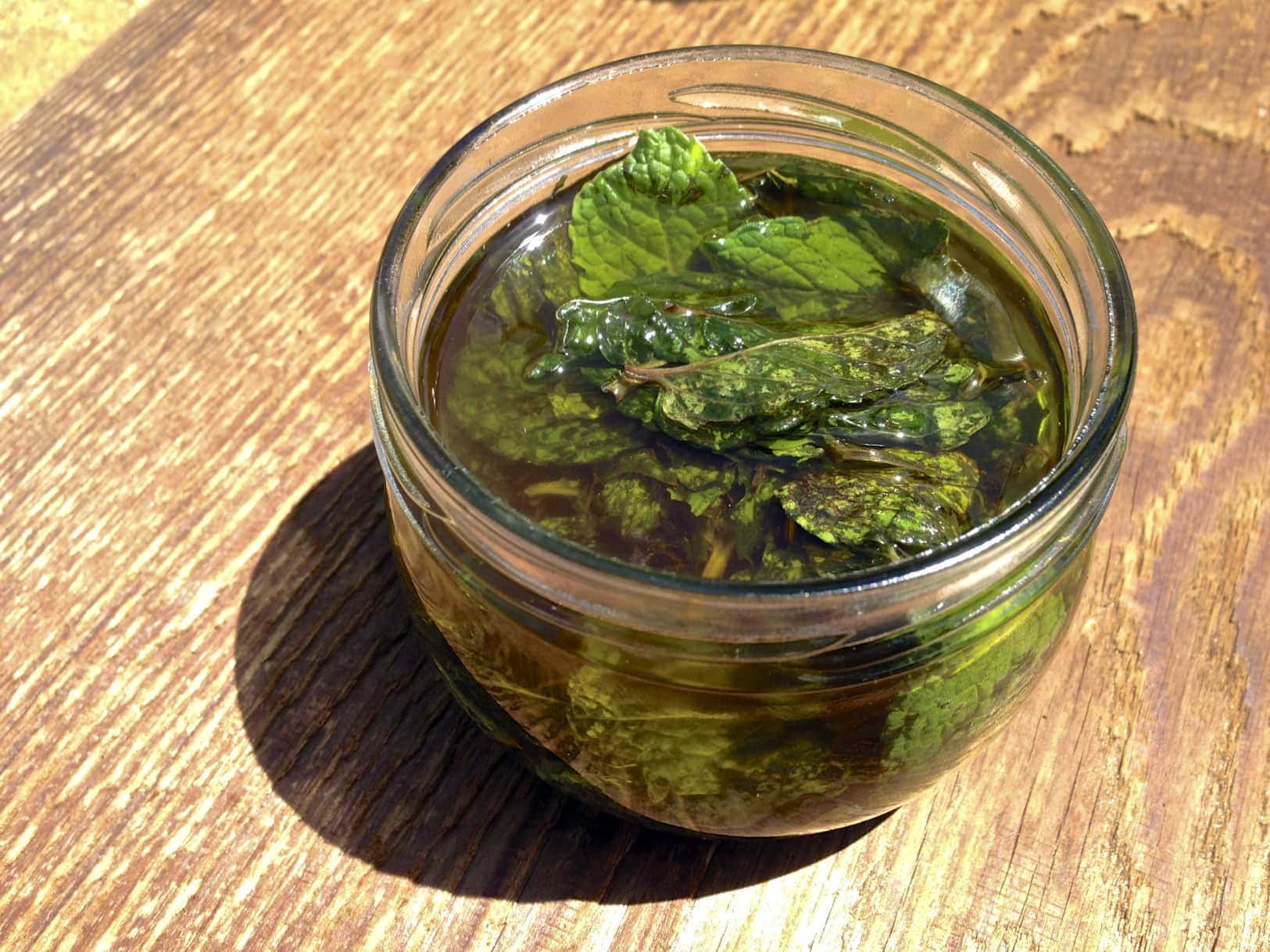 glass jar with peppermint leaves for making homemade peppermint oil