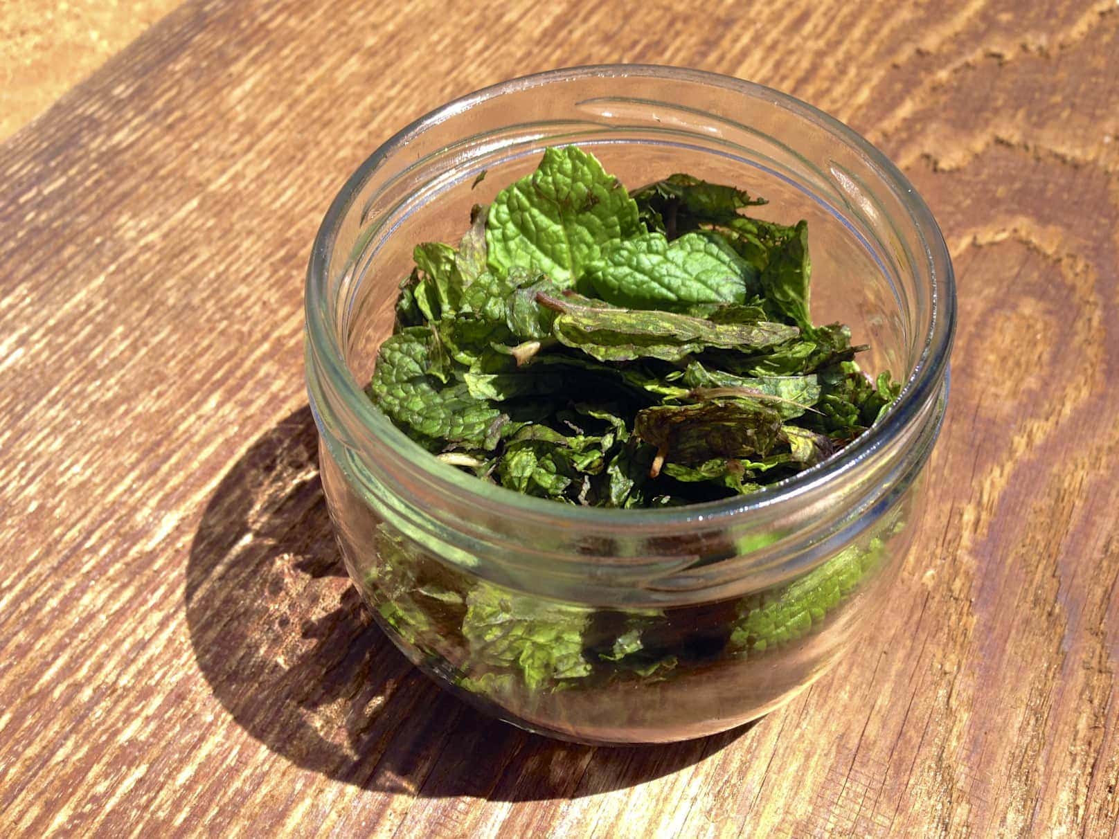glass jar with peppermint leaves for making homemade peppermint oil