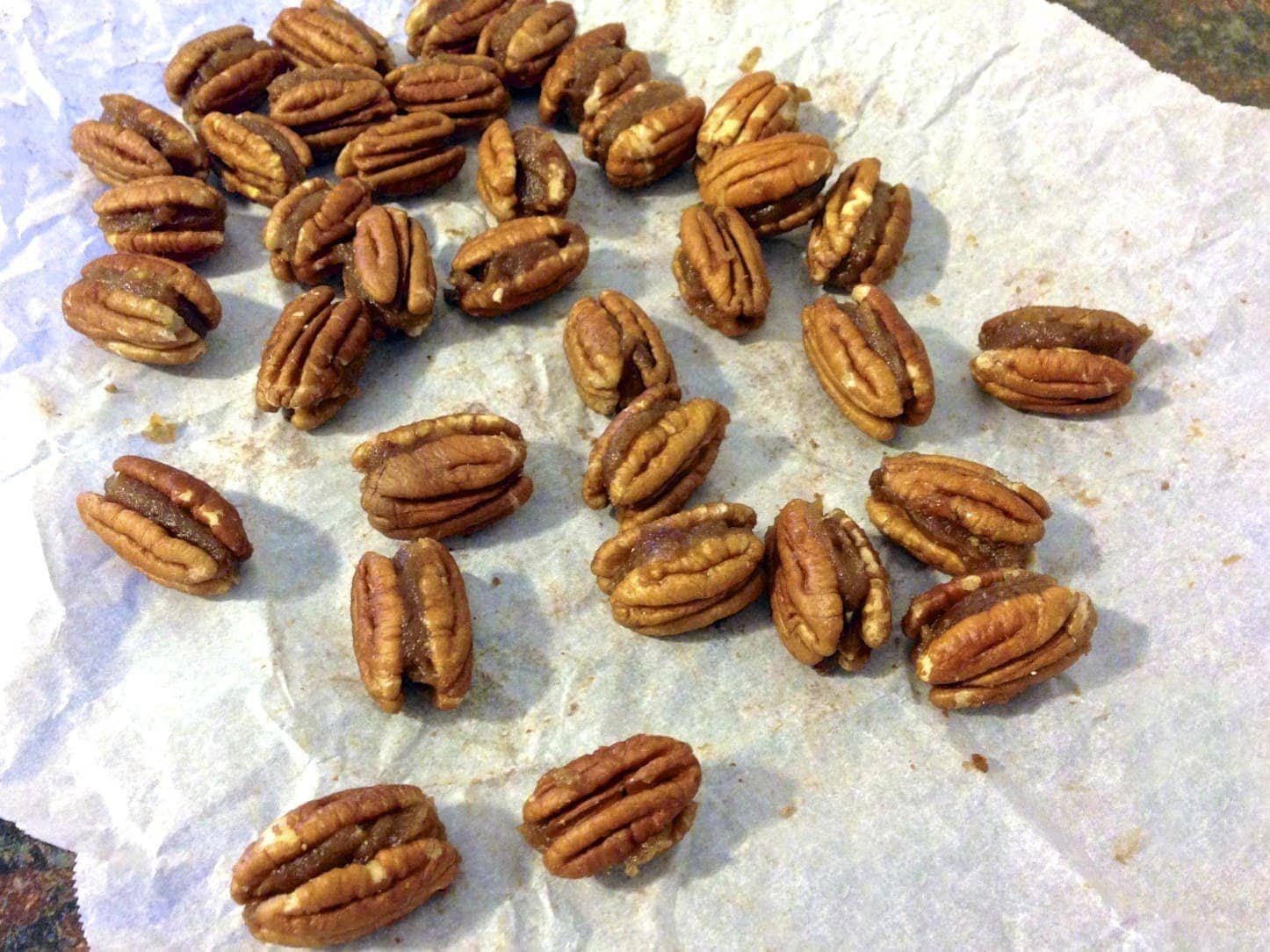 white napkin covered in caramel filled pecans waiting to be drizzled in chocolate