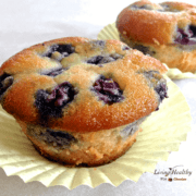 close up of two blueberry muffins in yellow paper muffin cup