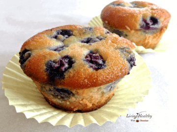 close up of two blueberry muffins in yellow paper muffin cup