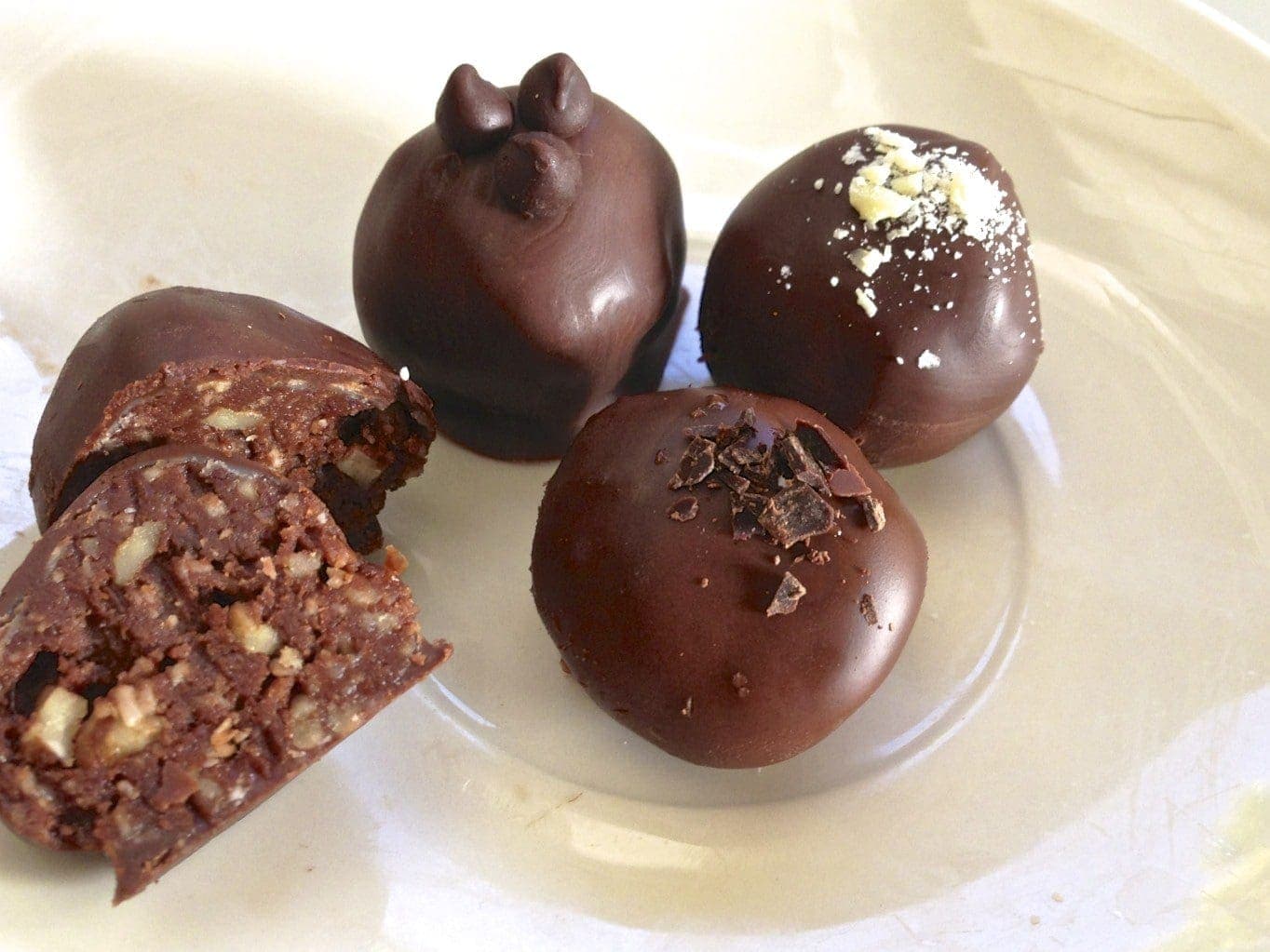 close up of paleo chocolate pecan crunch truffle on clear plate 