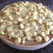 close up of a large complete paleo macadamia nut pie topped with full and chopped nuts
