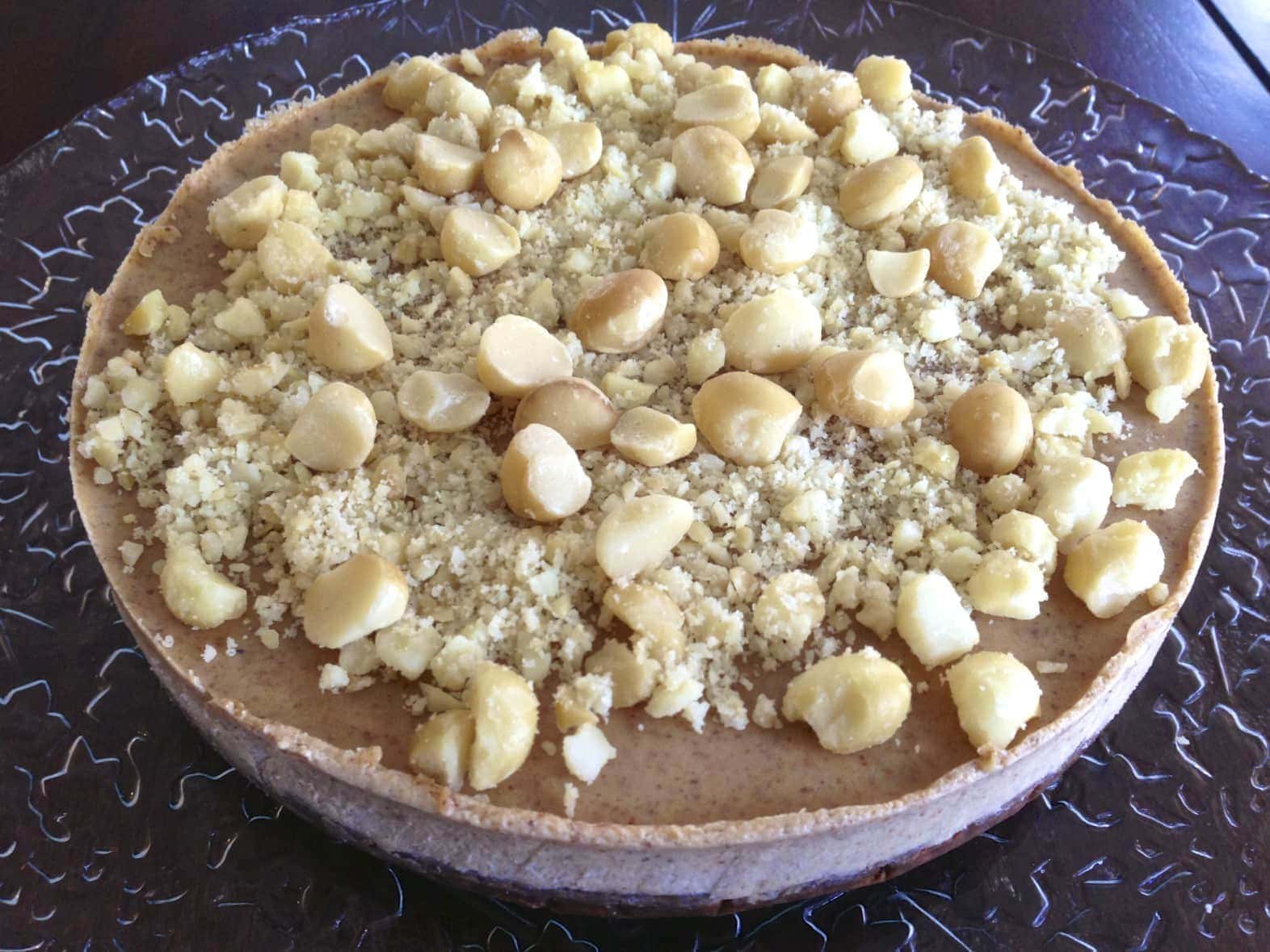 close up of a large complete paleo macadamia nut pie topped with full and chopped nuts