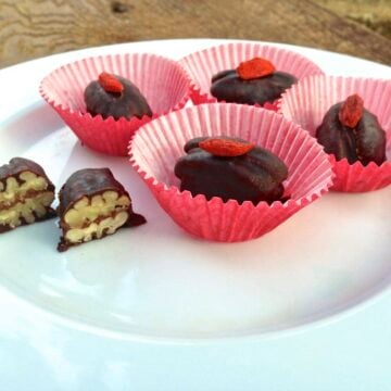 plate with chocolate caramel pecan candies in red paper cups with one by itself cut in half showing texture inside