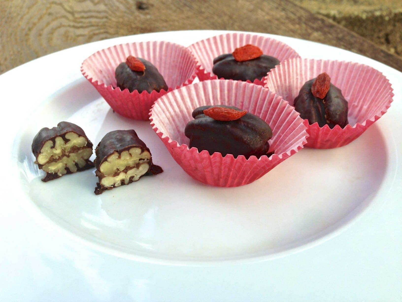 plate with chocolate caramel pecan candies in red paper cups with one by itself cut in half showing texture inside