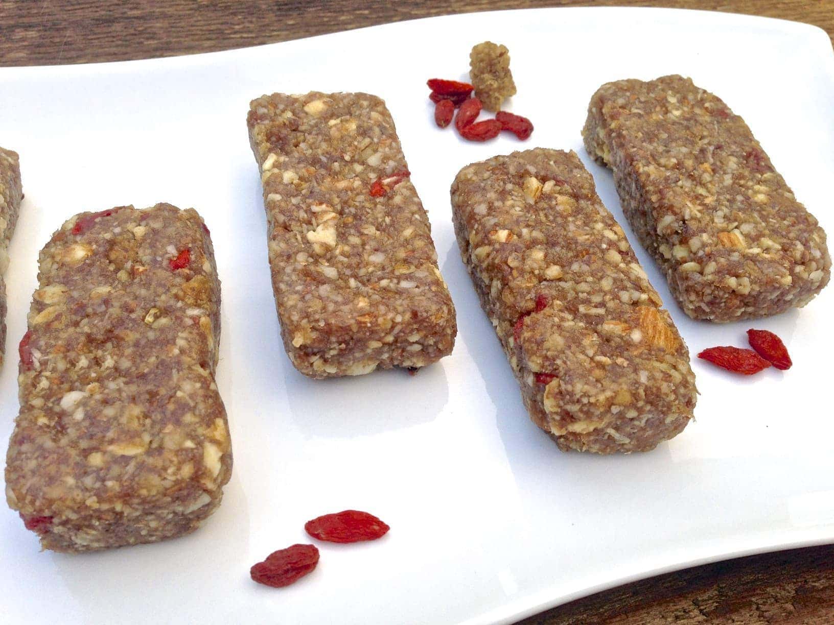 four pieces of paleo mulberry goji berry energy bars on white plate 