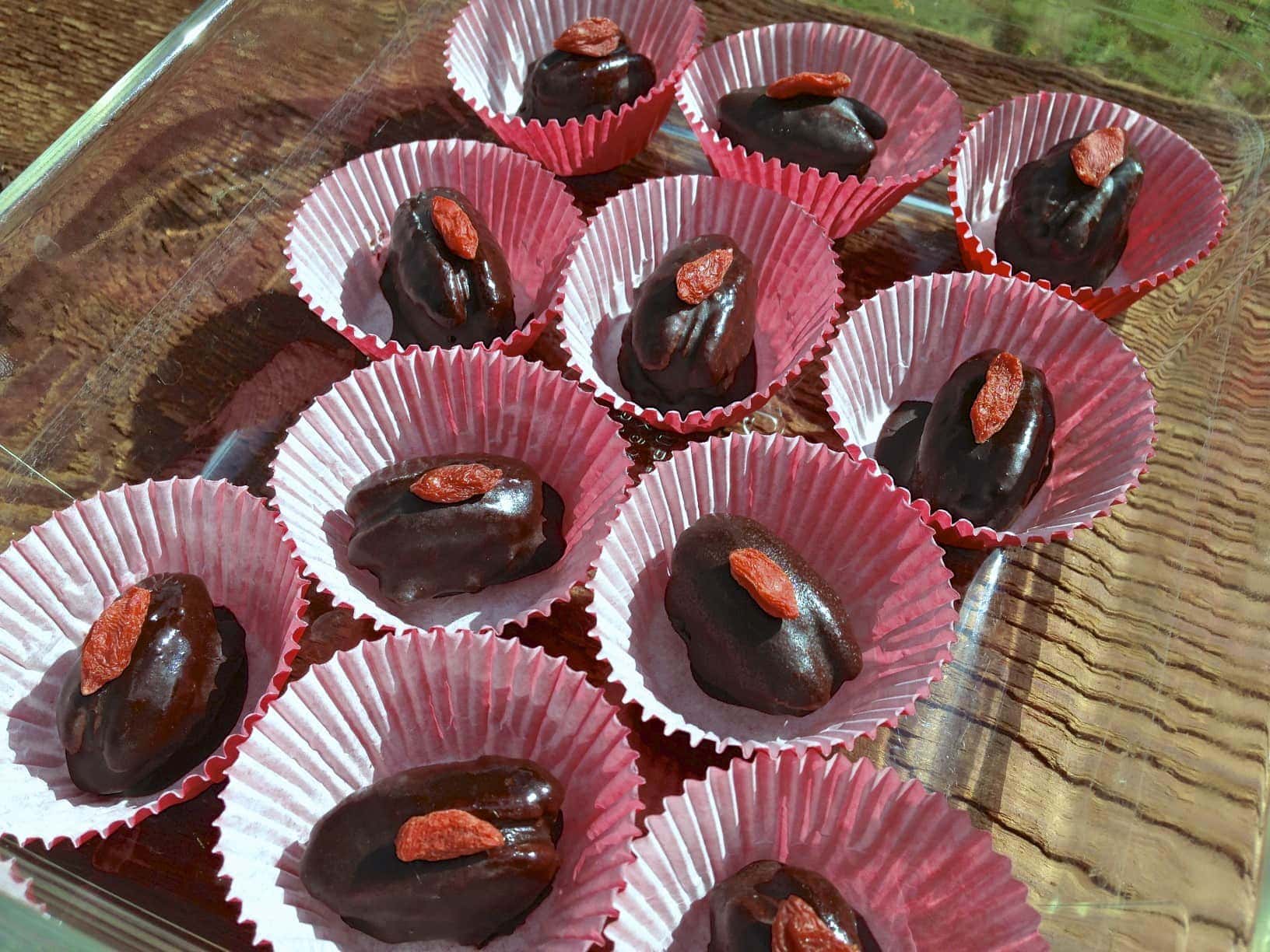 several rows of chocolate caramel pecan candies in red paper cups