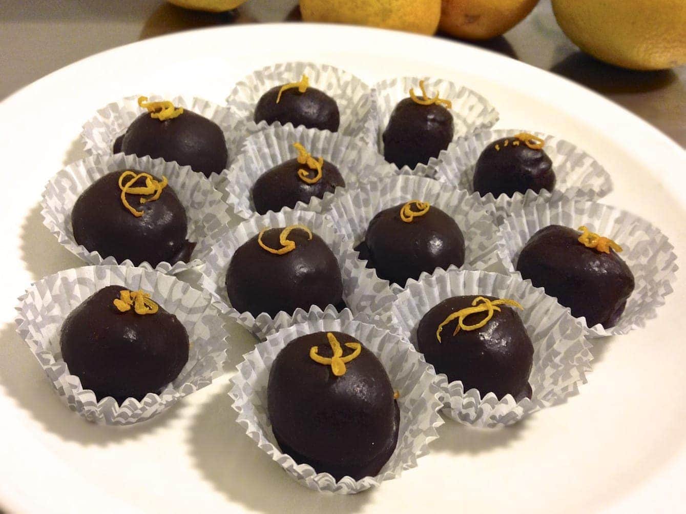 white plate with numerous dark chocolate orange bombs in paper cups