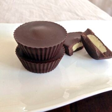 plate with stack of two paleo macadamia nut butter cups and one cup broken in half showing texture inside