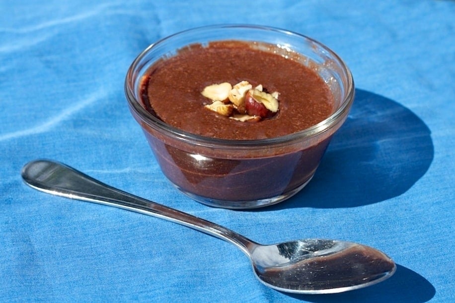 small glass dish filled with homemade paleo nutella on blue napkin with silver spoon in foreground 