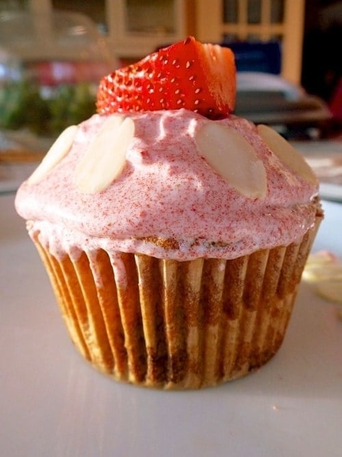 close up of paleo strawberry almond cupcake topped with frosting and a slice of strawberry