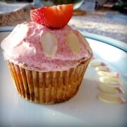 close up of paleo strawberry almond cupcake topped with frosting and a slice of strawberry