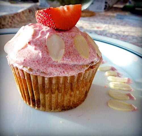 close up of paleo strawberry almond cupcake topped with frosting and a slice of strawberry