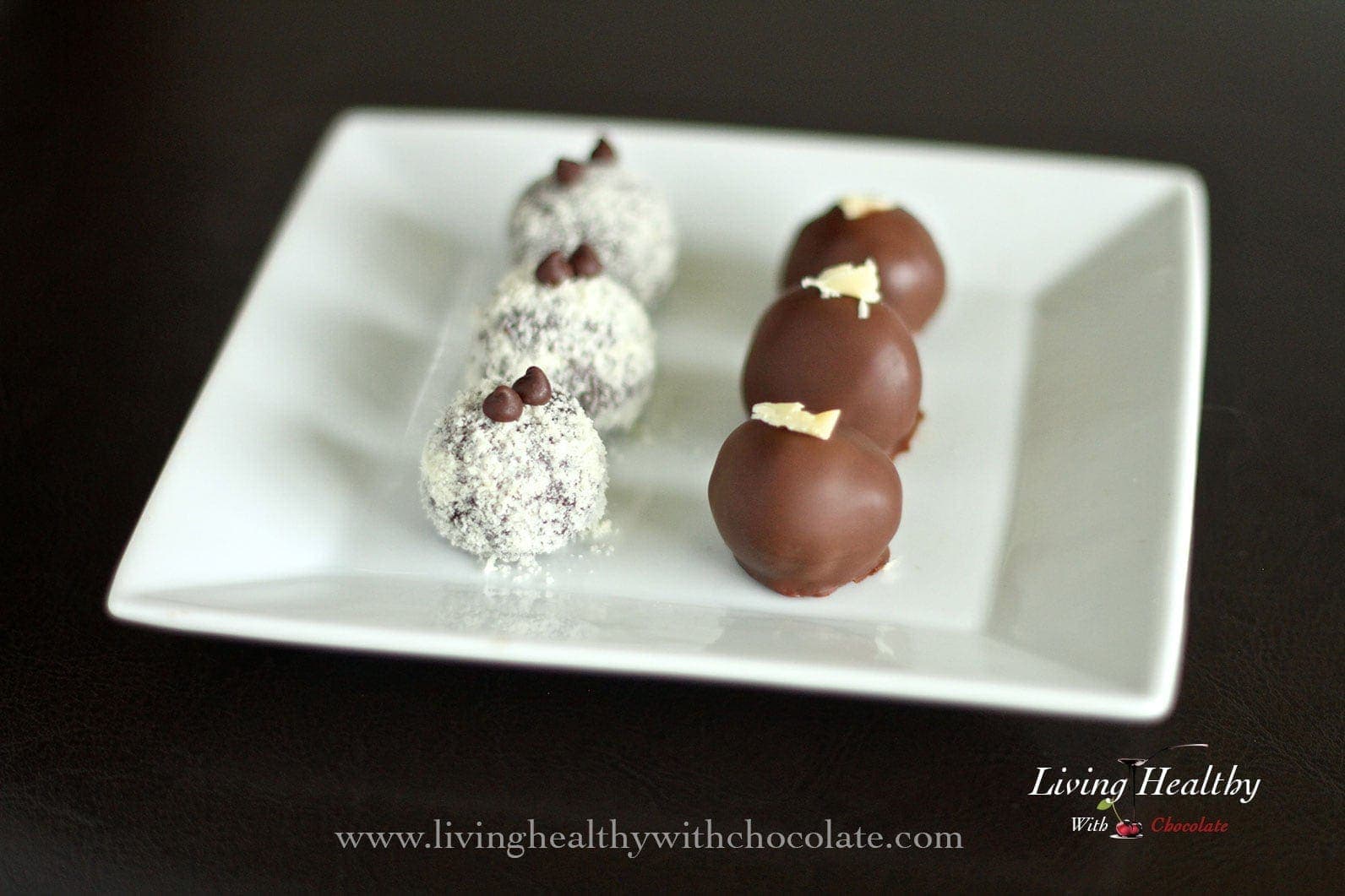 six paleo prune truffles on square plate with a black background 