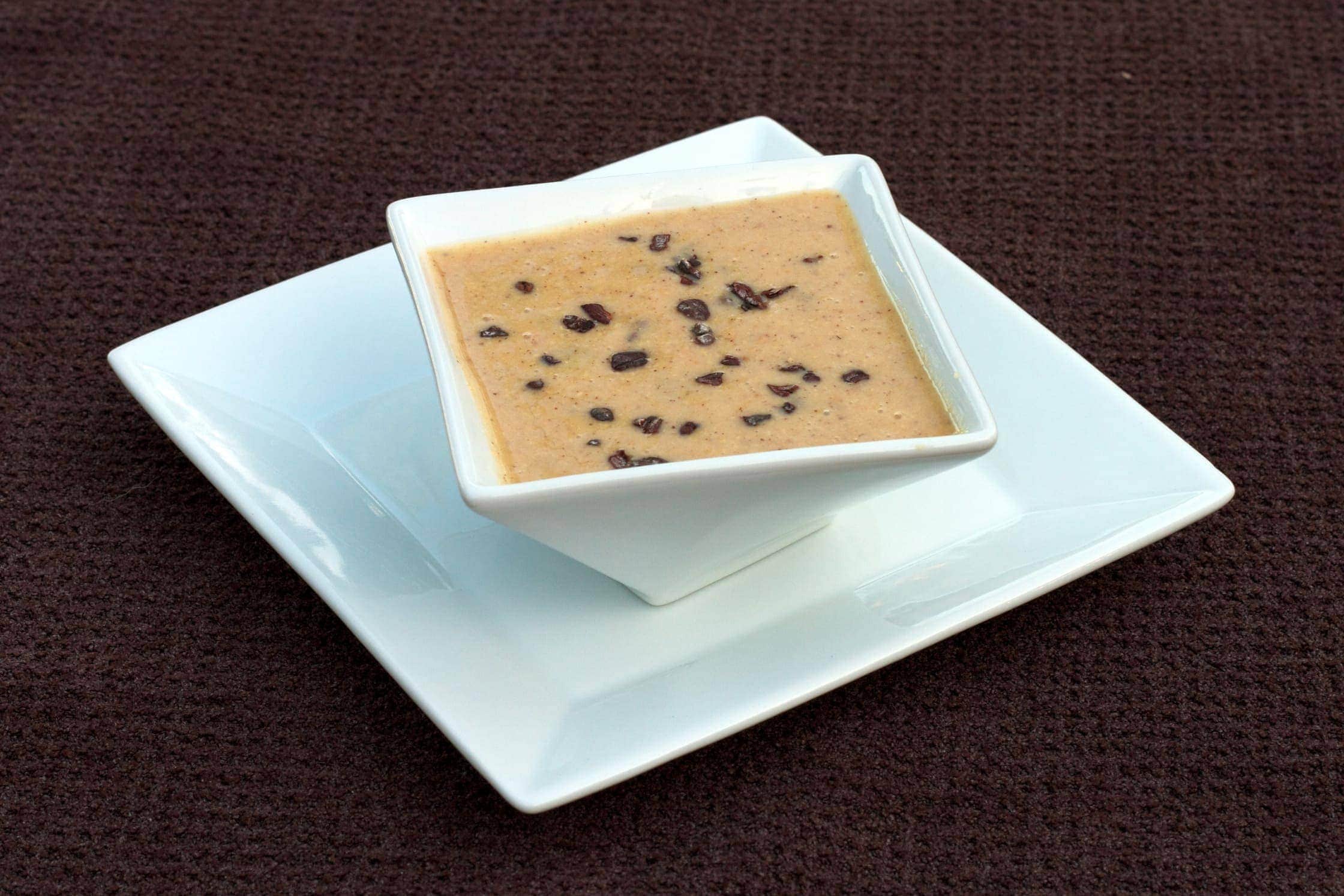 square dish on plate filled with coconut hazelnut bitter with cacao nibs 