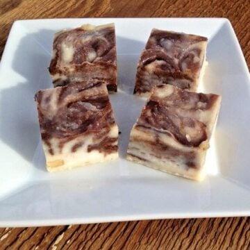 four pieces of macadamia nut butter chocolate swirl fudge bites on a white plate on top of wooden table