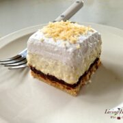 slice of coconut cream pie topped with whipped cream with a fork in background