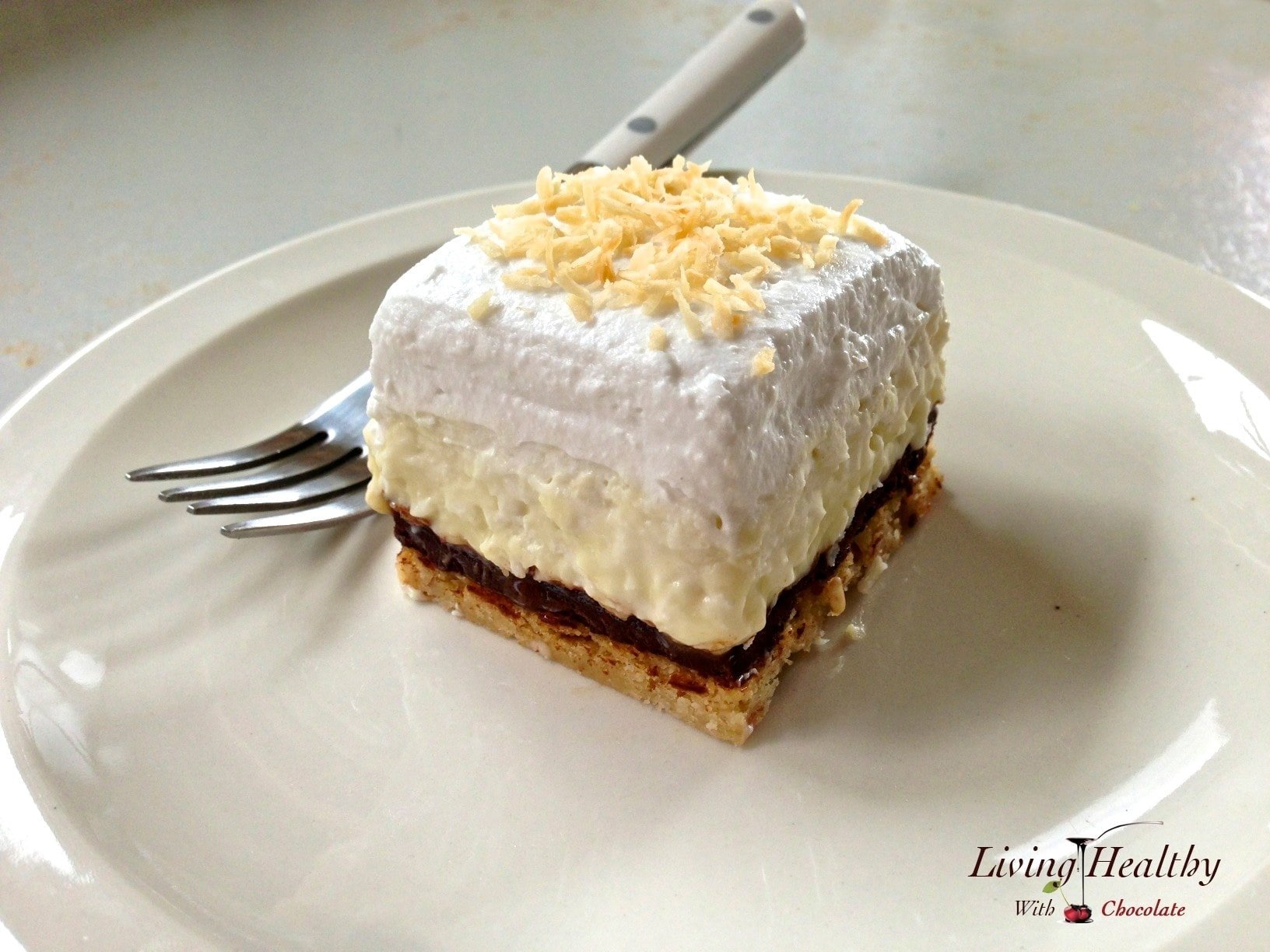 slice of coconut cream pie topped with whipped cream with a fork in background  