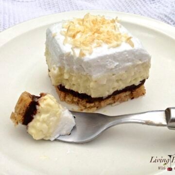 slice of coconut cream pie topped with whipped cream with small bite resting on a fork in foreground