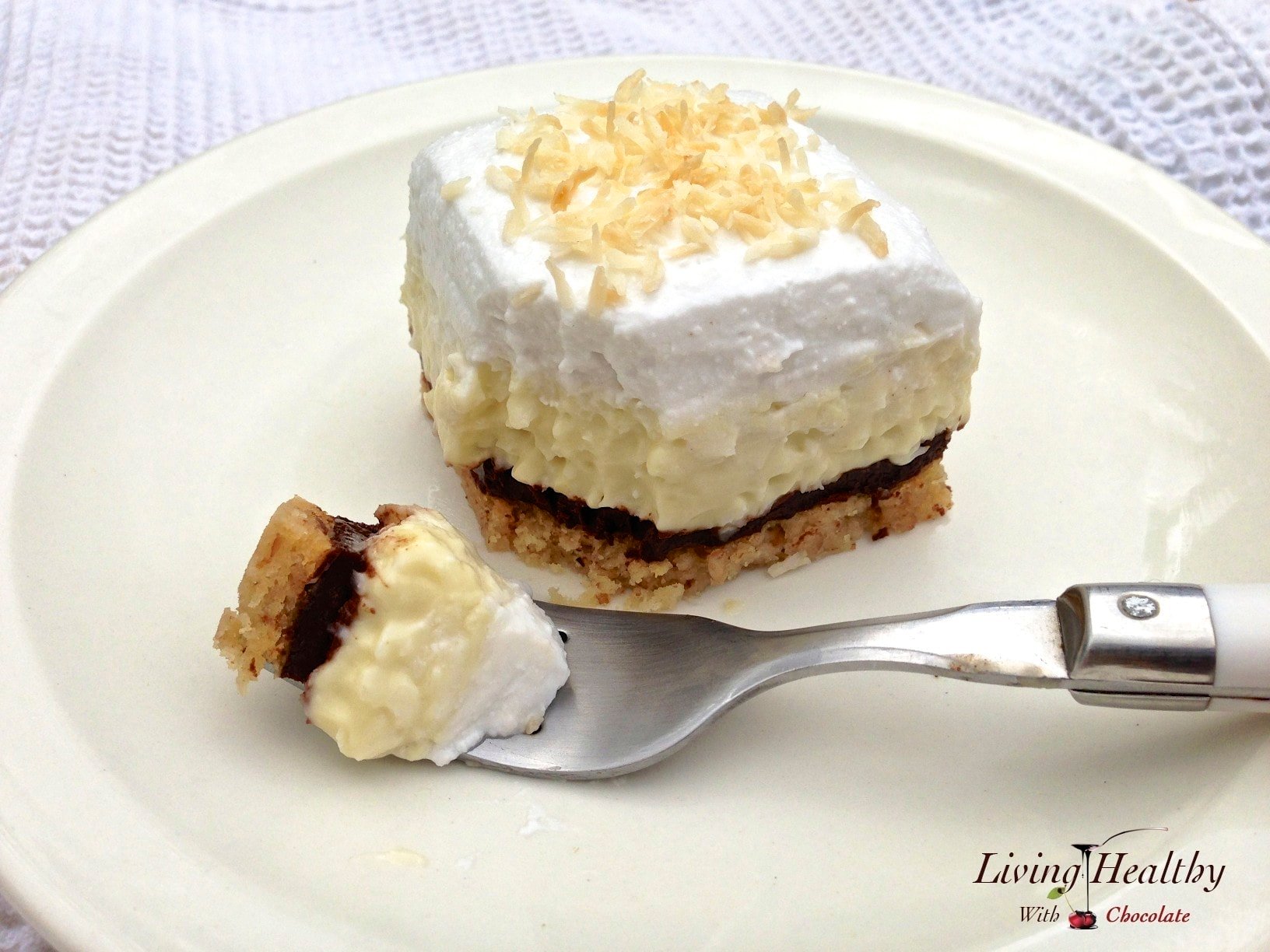 slice of coconut cream pie topped with whipped cream with small bite resting on a fork in foreground 