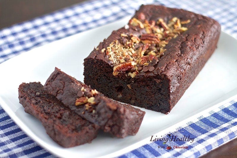 loaf of paleo chocolate zucchini bread on white serving dish with blue checkered napkin underneath 