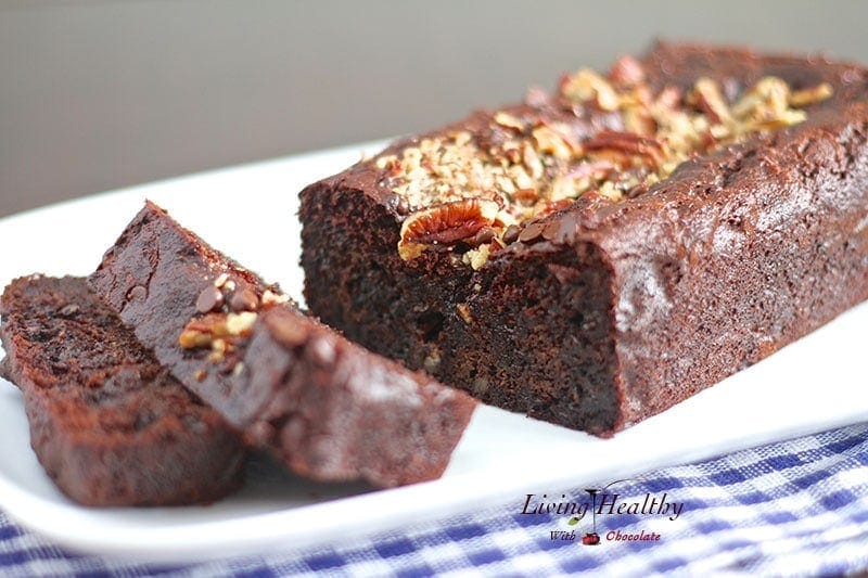 loaf of paleo chocolate zucchini bread on white serving dish with blue checkered napkin underneath 