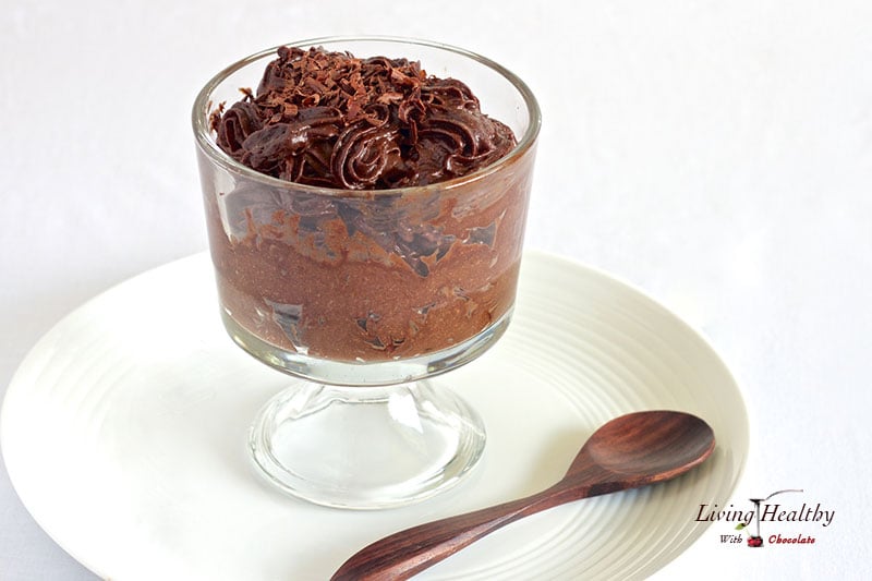 glass serving dish filled with chocolate banana mousse on round plate with wooden spoon