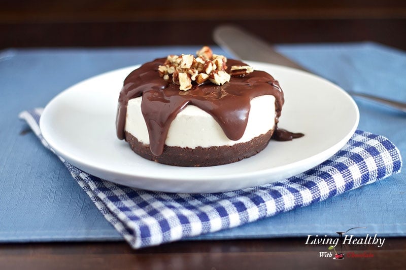 white plate with paleo brownie ice cream cake topped with melted chocolate and chopped nuts with blue napkin