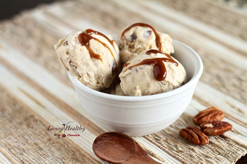 bowl of pecan butter caramel ice cream drizzled with homemade caramel and a wooden spoon in foreground 