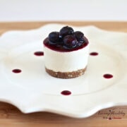 plate with a single serving raw no bake blueberry cheesecake topped with blueberry sauce and fresh blueberries