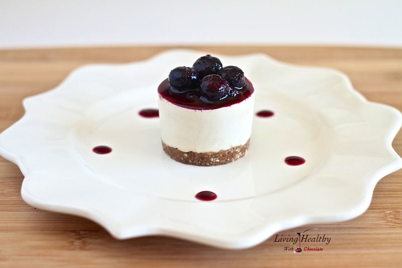 plate with a single serving raw no bake blueberry cheesecake topped with blueberry sauce and fresh blueberries