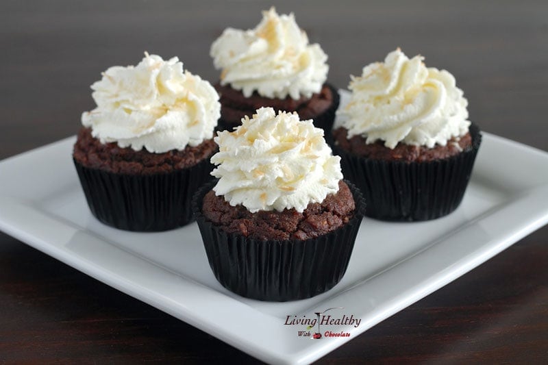 plate with four paleo coconut cupcakes topped with whipped cream