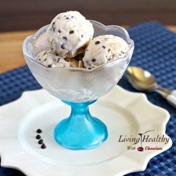 glass serving bowl filled with three scoops of chocolate chop cookie dough ice cream on white place with blue placemat